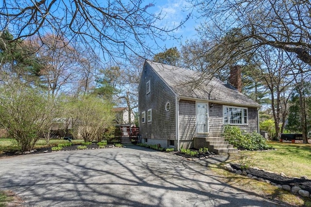 view of property exterior featuring a chimney, driveway, and roof with shingles