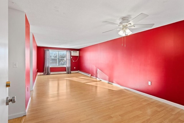 spare room with a wall unit AC, ceiling fan, light hardwood / wood-style flooring, and a baseboard heating unit