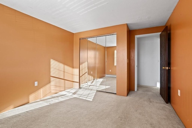 unfurnished bedroom featuring baseboard heating, light carpet, and a closet