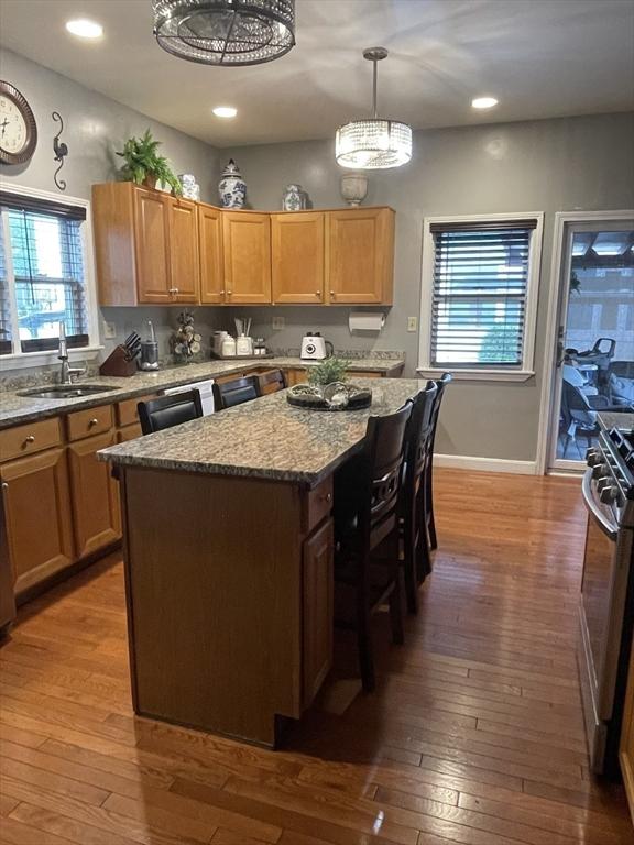 9 Cedar St, Lynn, MA 01905 - kitchen featuring stainless steel gas range oven, hardwood / wood-style flooring, stone countertops, a kitchen island, and plenty of natural light