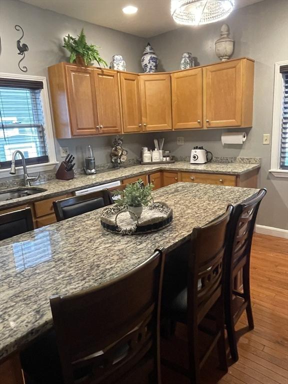 9 Cedar St, Lynn, MA 01905 - kitchen with light wood-type flooring, light stone countertops, a kitchen bar, and plenty of natural light