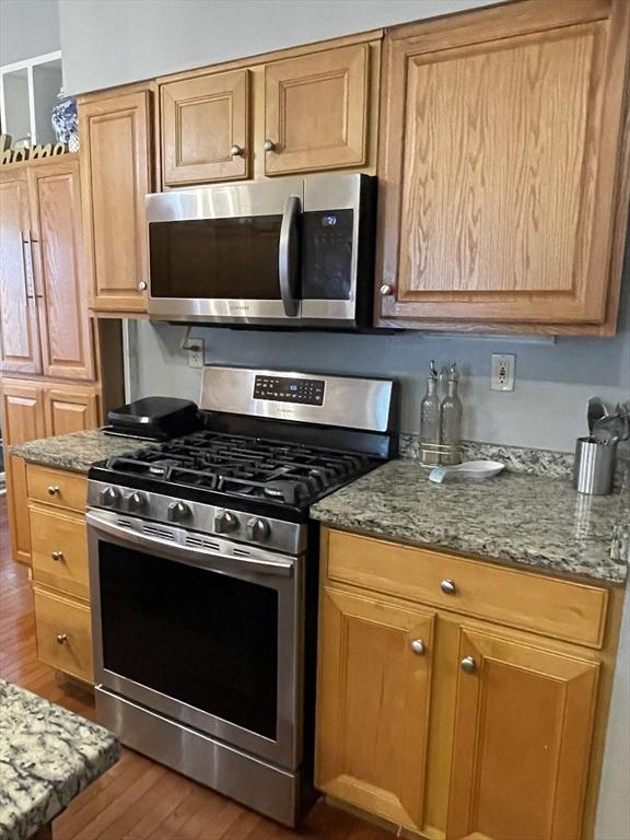 9 Cedar St, Lynn, MA 01905 - kitchen with stainless steel appliances, wood finished floors, and light stone counters