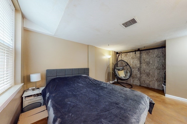 carpeted bedroom featuring a textured ceiling, a barn door, and lofted ceiling