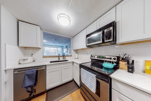 kitchen featuring backsplash, white cabinetry, sink, and stainless steel appliances