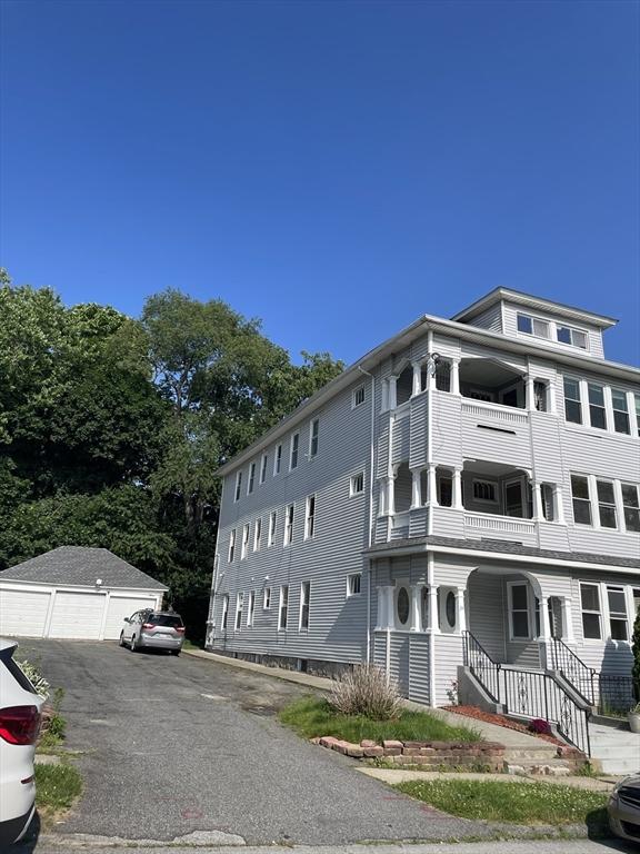 view of front of home featuring a garage, an outbuilding, and a balcony