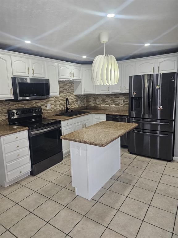 kitchen featuring light tile patterned flooring, sink, decorative light fixtures, black appliances, and white cabinets