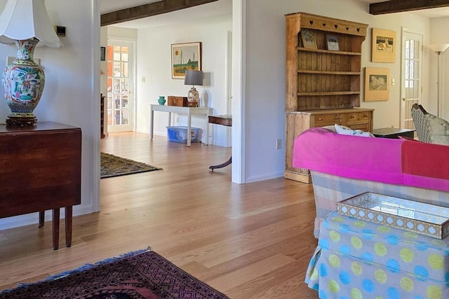 interior space with beam ceiling and light hardwood / wood-style flooring