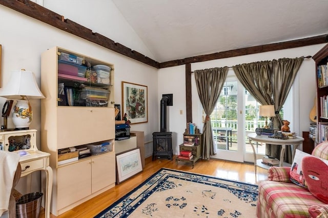 living room featuring vaulted ceiling, light hardwood / wood-style floors, and a wood stove