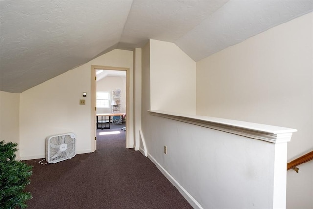 corridor with dark carpet, a textured ceiling, and vaulted ceiling