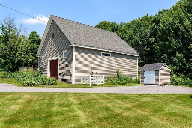 view of side of property with a yard and a storage unit