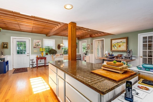 kitchen featuring baseboard heating, white cabinetry, dark stone counters, beamed ceiling, and light hardwood / wood-style floors