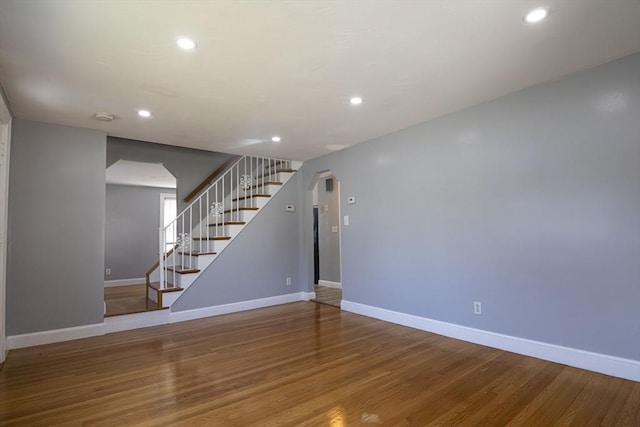 33 Altoona Rd, Dedham, MA 02026 - unfurnished living room featuring arched walkways, baseboards, recessed lighting, stairs, and wood finished floors