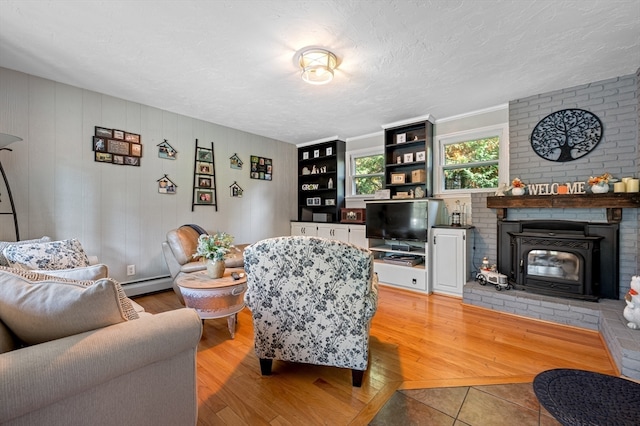 living room featuring a brick fireplace, wood-type flooring, a textured ceiling, and baseboard heating