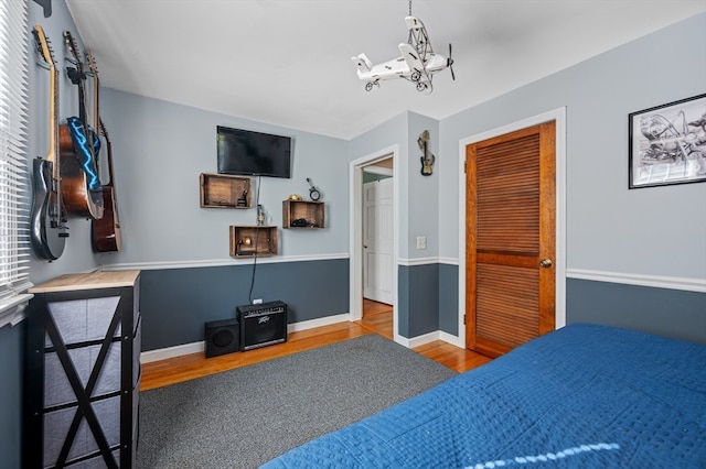 bedroom with hardwood / wood-style floors, a closet, and a notable chandelier