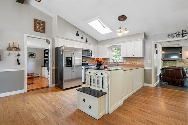 kitchen with decorative light fixtures, stainless steel appliances, light hardwood / wood-style flooring, and white cabinetry