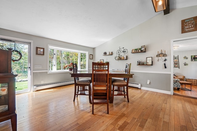 dining room featuring light hardwood / wood-style flooring, vaulted ceiling, and a baseboard heating unit