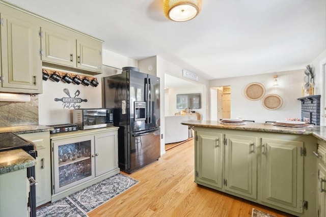 kitchen with tasteful backsplash, green cabinets, a toaster, light wood-type flooring, and black fridge with ice dispenser