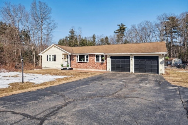 single story home with aphalt driveway, brick siding, and a garage