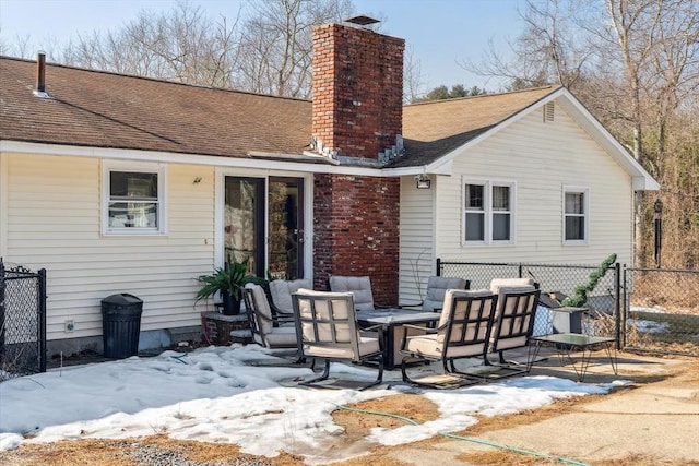 snow covered property featuring a shingled roof, a chimney, a patio, and fence