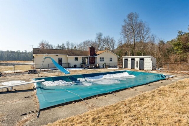 view of pool featuring a fenced in pool, fence, a water slide, a diving board, and a patio area