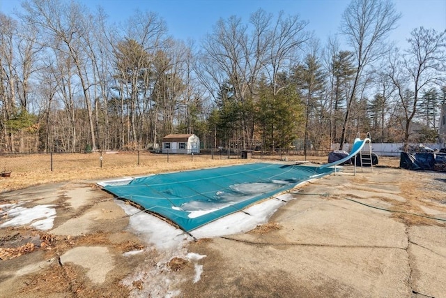 view of swimming pool featuring a fenced in pool, fence, a water slide, an outdoor structure, and a patio area