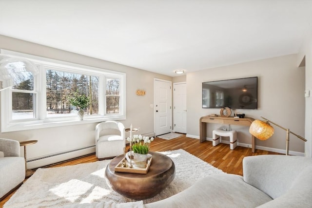 living area with baseboard heating, baseboards, and wood finished floors