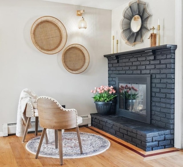 sitting room featuring baseboards, a brick fireplace, and wood finished floors