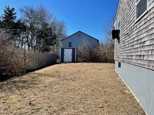 view of yard featuring a shed, fence, and an outbuilding