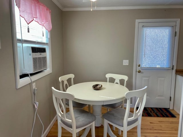 dining room featuring cooling unit, crown molding, baseboards, and wood finished floors