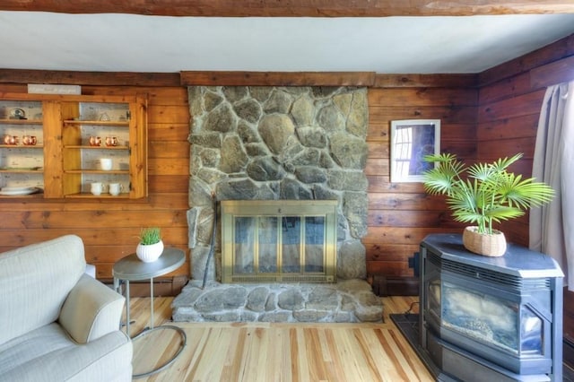 living area with wood finished floors, a wood stove, and a fireplace
