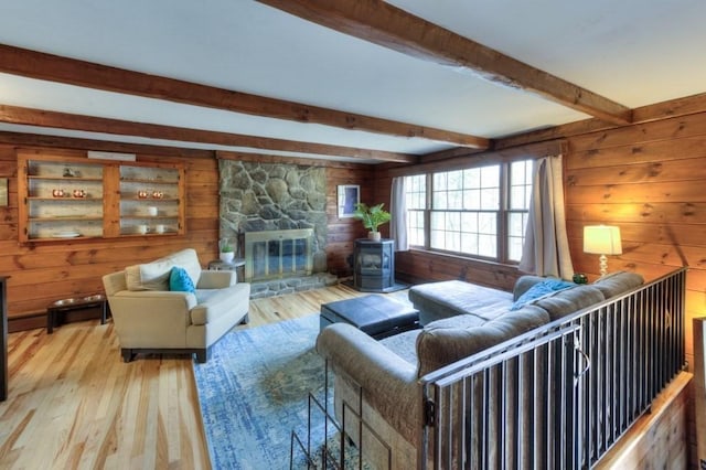 living area with wooden walls, beam ceiling, and hardwood / wood-style floors