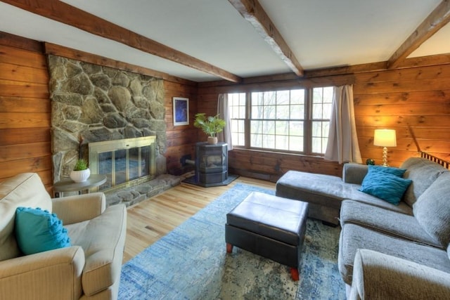living area featuring wood finished floors, wooden walls, and beam ceiling