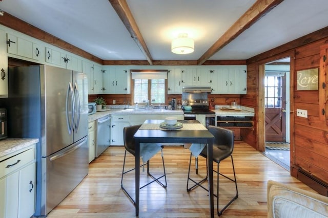 kitchen featuring light countertops, under cabinet range hood, a healthy amount of sunlight, and stainless steel appliances