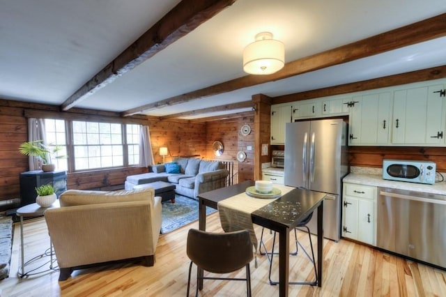 kitchen with wood walls, light countertops, beamed ceiling, light wood-style floors, and stainless steel appliances