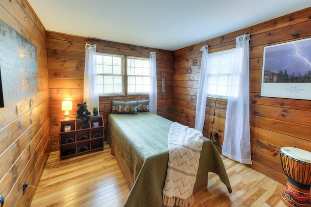 bedroom with wood walls and light wood finished floors