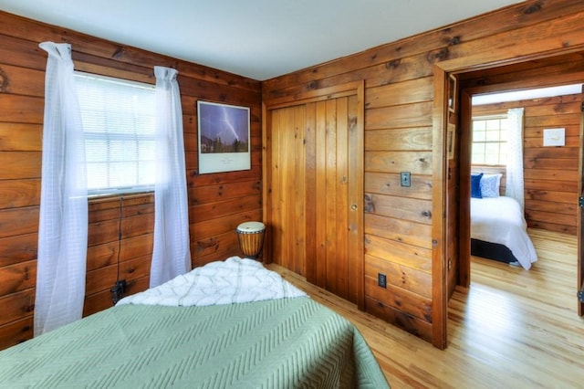 bedroom featuring a closet, light wood finished floors, and wooden walls