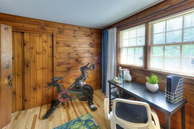 exercise area with wood walls and light wood finished floors