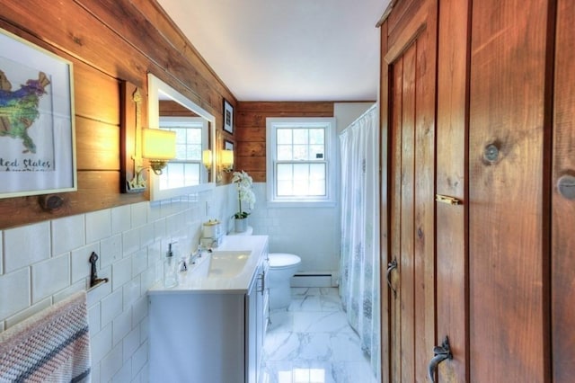 bathroom with baseboard heating, wood walls, vanity, toilet, and marble finish floor