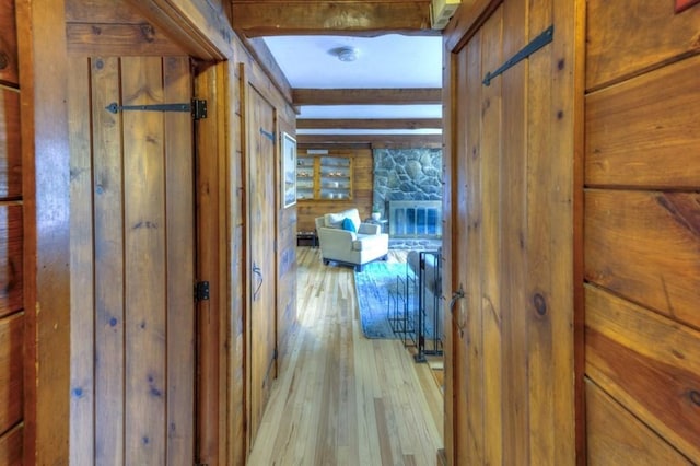 hallway featuring wood walls, hardwood / wood-style flooring, and beam ceiling