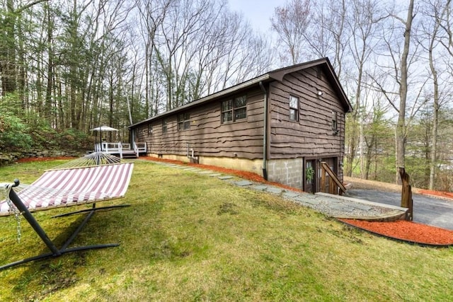 view of side of home with a yard, driveway, and a wooden deck