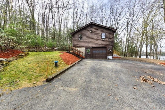 view of side of home featuring an attached garage, driveway, and stairs