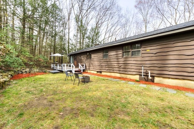 view of yard with a wooden deck and a fire pit