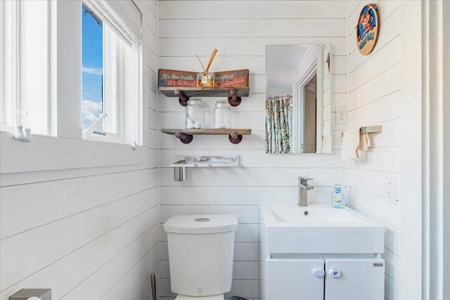 bathroom featuring vanity, toilet, and wooden walls