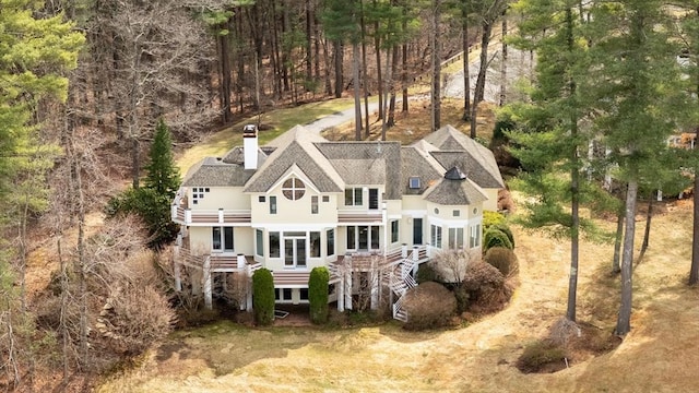 44 Southpoint Ln, Ipswich, MA 01938 - back of property with a balcony, a shingled roof, a chimney, and a forest view
