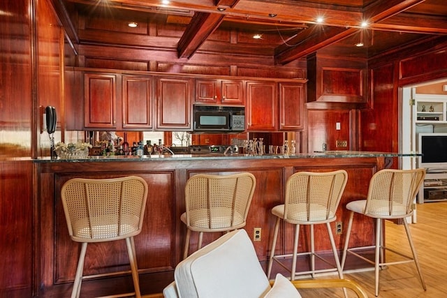 44 Southpoint Ln, Ipswich, MA 01938 - kitchen with black microwave, reddish brown cabinets, wood walls, coffered ceiling, and dark countertops