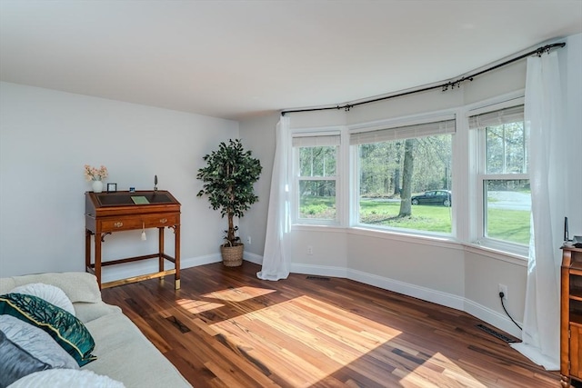 living area with a healthy amount of sunlight, baseboards, and dark wood-style flooring
