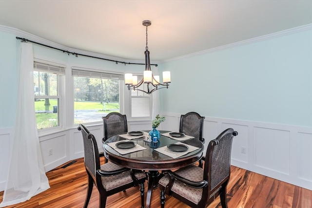 dining space featuring a chandelier, wood finished floors, and a decorative wall