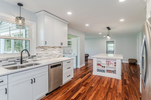 kitchen with appliances with stainless steel finishes, a sink, light countertops, white cabinetry, and decorative backsplash