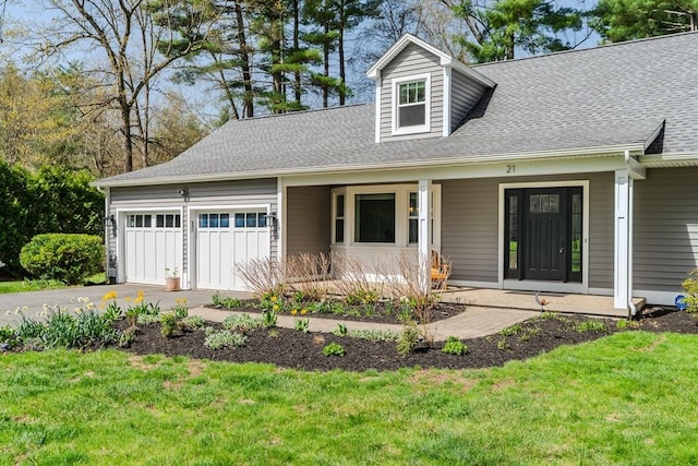 view of front of house with covered porch, roof with shingles, a garage, aphalt driveway, and a front lawn
