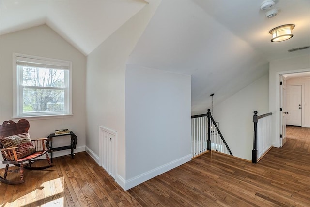 additional living space with baseboards, visible vents, wood finished floors, and lofted ceiling